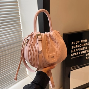 Gros plan du sac seau plissé rose avec textures ondulées et poignée supérieure
