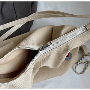 Dettaglio della cerniera argentata e trama della borsa tote in tela beige
