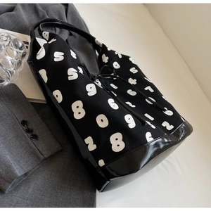 Detail of black and white canvas tote bag featuring large numbers and leather base