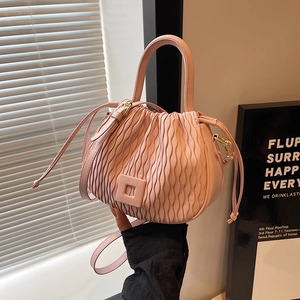 Détail de ce sac seau plissé rose avec texture gaufrée verticale et bandoulière amovible