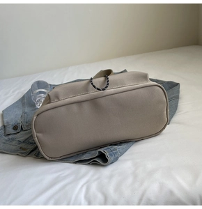 Détail du fond d'un sac cabas en toile kaki avec cordon tressé noir et blanc décoratif