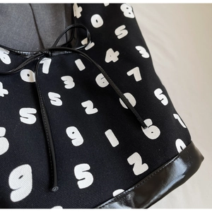 Close-up of number print canvas bag featuring leather trim and drawstring detail