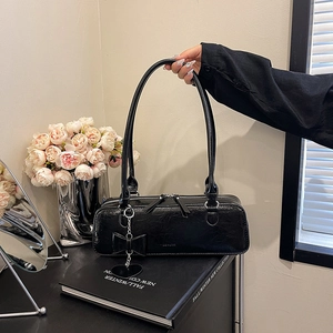 Détail du sac à main en cuir verni noir avec boucles argentées et nœud décoratif
