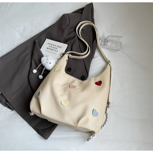 Dettaglio borsa hobo beige con toppe a cuore colorate e ciondolo a nuvola morbida