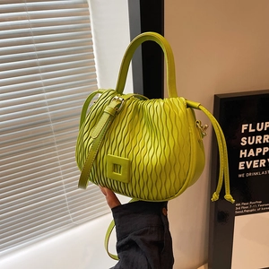 Détail d'un sac seau en cuir vert vif avec plis ondulés texturés et bandoulière réglable