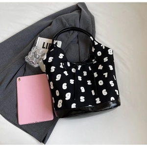 Detailed shot of black canvas tote bag with white number prints on grey blazer