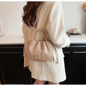 Détail d'un sac seau plissé beige avec boucle carrée et accents de cordon latéraux