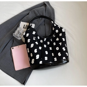 Close-up of black canvas tote bag featuring white numeric print and leather drawstring