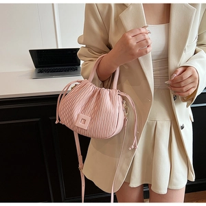 Détail d'un sac seau rose clair plissé avec bandoulière réglable et texture chic