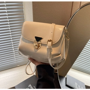 Détail d'un sac plissé blanc crème avec fermoir en métal doré et motif triangulaire chic