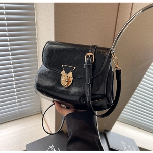 Détail du sac bandoulière en cuir verni noir plissé avec une boucle en métal doré