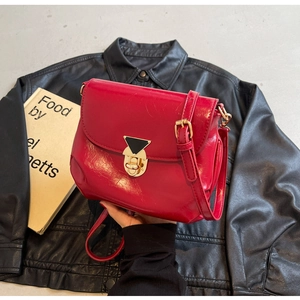 Détail du sac à bandoulière en cuir rouge brillant avec boucle en métal doré élégante