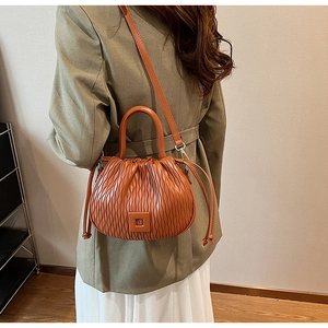 Sac seau nuage plissé caramel porté à l'épaule et à la main par un mannequin