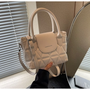 Close-up of quilted cream bucket bag with top handles and adjustable shoulder strap