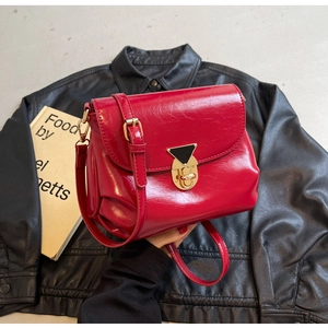Détail du sac bandoulière vintage rouge avec boucle dorée triangulaire et fini brillant
