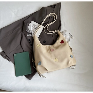 Dettaglio della borsa tote in tela beige con cuori 3D colorati e catena argentata