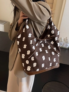 Brown canvas bucket bag with white numeric pattern and drawstring on a model