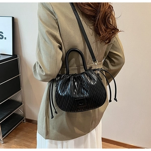 Détail du sac seau plissé noir avec fermoir métallique et bandoulière réglable