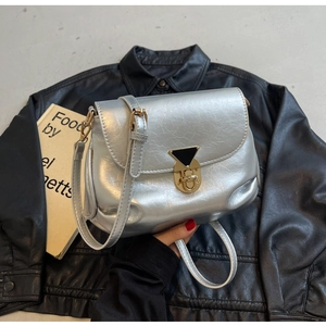 Gros plan du sac bandoulière argenté plissé avec fermoir doré sur du cuir noir mat
