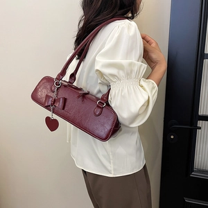 Détail du sac à bandoulière bordeaux avec nœud et chaîne à cœur sur cuir plissé