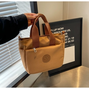 Détail d'un sac cabas en nylon marron avec logo vélo circulaire et poche extérieure zippée