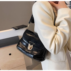 Détail du sac à bandoulière plissé noir brillant avec fermoir pivotant triangulaire doré