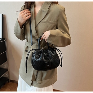 Détail du sac seau plissé noir avec boucle carrée en métal et texture ondulée