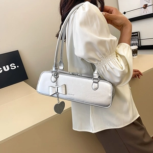 Détail d'un sac argenté métallisé avec nœud, pendentif cœur et texture cuir craquelé