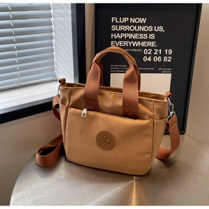 Détail du sac fourre-tout en nylon kaki avec poche zippée et logo en cuir sur une table en métal