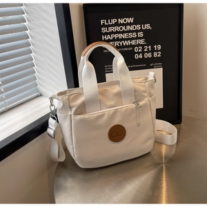 Vue détaillée du sac à bandoulière en toile blanc cassé avec logo en cuir marron