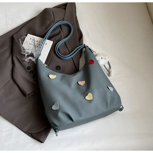 Dettaglio borsa hobo blu con toppe a cuore colorate e ciondolo a nuvola