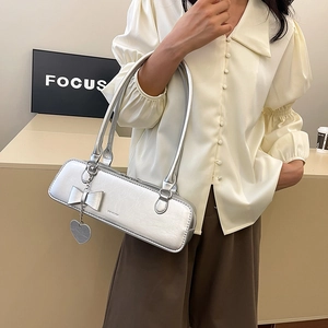 Sac baguette argenté métallisé avec pendentif cœur porté comme un sac d'épaule tendance