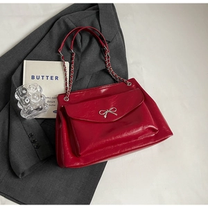Detailed shot of red glossy tote bag featuring a silver bow buckle and chain strap