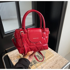Detail of red quilted bucket bag with dual handles and polished finish on a modern countertop