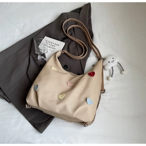Dettaglio della borsa in tela beige con toppe a cuore colorate e ciondolo a nuvola