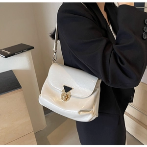 Détail du sac bandoulière en cuir verni blanc avec boucle dorée et design plissé chic