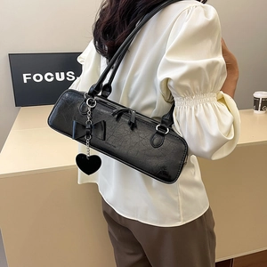 Vue latérale d'un sac à bandoulière noir en cuir huilé avec nœud et breloque cœur