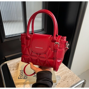 Detail of red quilted patent leather handbag with white Fashion & Bags text on the flap
