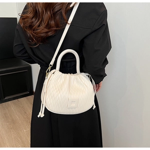 Détail du sac seau crème montrant la texture plissée et les ferrures dorées