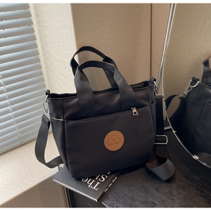 Gros plan sur le sac bandoulière en nylon noir avec logo en cuir et détails argentés