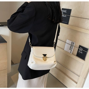 Détail d'un sac à bandoulière crème avec fermoir en métal et finition brillante