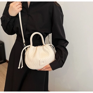 Modèle portant un sac seau crème froncé avec boucle carrée et fine bandoulière