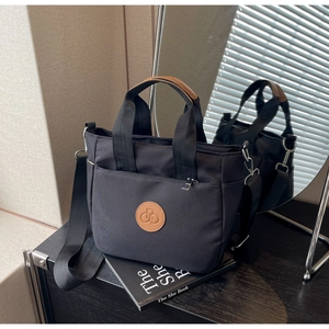 Détail du sac cabas en nylon noir avec logo en cuir et bandoulière réglable