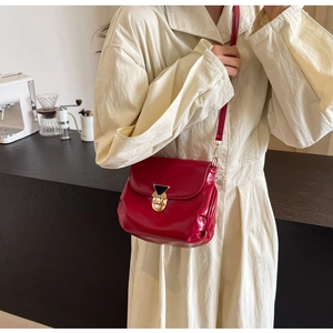 Détail du sac bandoulière froncé en cuir rouge avec boucle dorée sur un mannequin