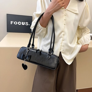 Détail du sac hobo noir en similicuir vintage avec nœud et breloque cœur métallique