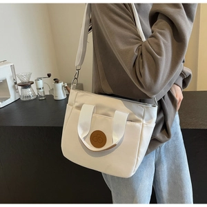 Photo lifestyle d'un sac cabas en toile blanche avec écusson en cuir brun et logo vélo
