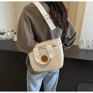 Gros plan d'un sac cabas en toile blanche avec bandoulière réglable et poches latérales