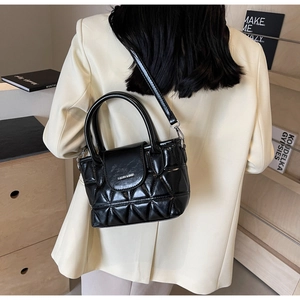 Close-up of a black quilted bucket bag featuring a sleek glossy finish and round handles