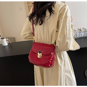 Détail du sac à bandoulière en cuir rouge avec fermoir doré et élégants plis sur le côté