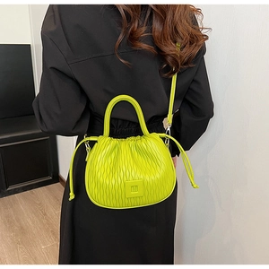 Gros plan détaillé d'un sac seau vert néon plissé avec une poignée ronde rigide